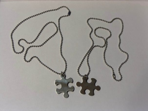 Zwei Puzzlestücke als Anhänger an Ketten, silber