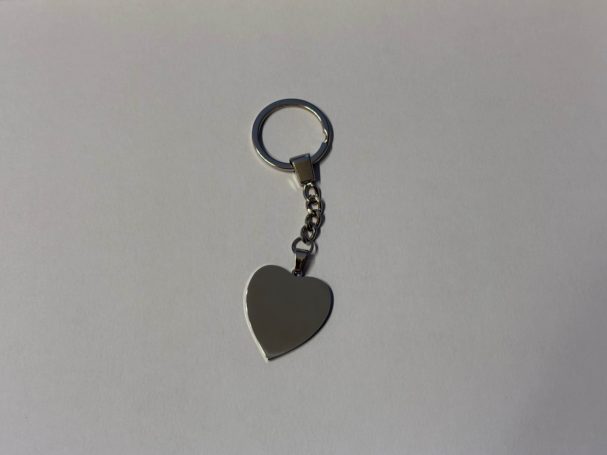 Silberner Schlüsselanhänger in Herzform mit einer Verzierungs-kette.
