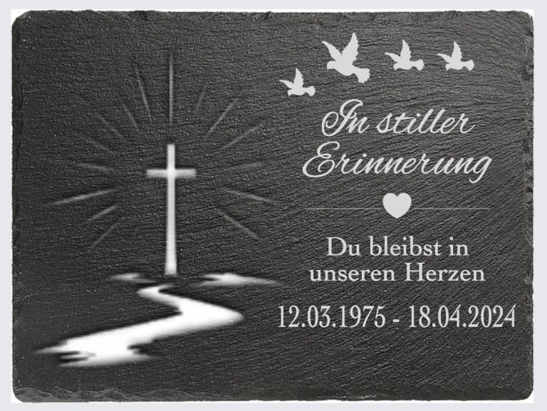 Ein Gedenkstein mit Kreuz, Vögeln und Text zur Erinnerung an einen geliebten Menschen.
