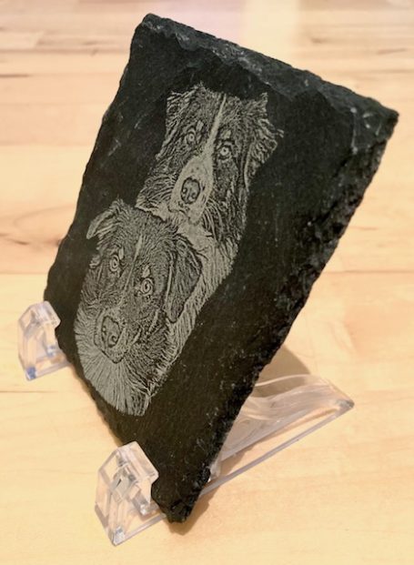 Gravierte Steinplatte mit Abbildungen von zwei Hunden.