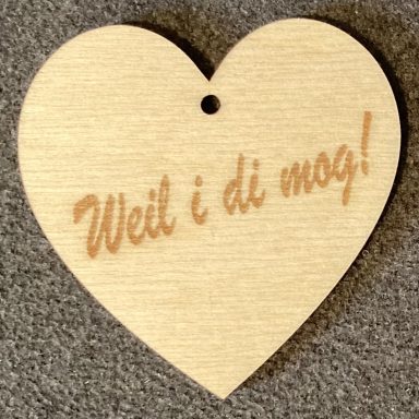 Holzscheibe in Herzform mit dem Schriftzug "Weil i di mog!"
