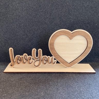 Holzschild mit der Aufschrift „love You“ und einem herzförmigen Rahmen.