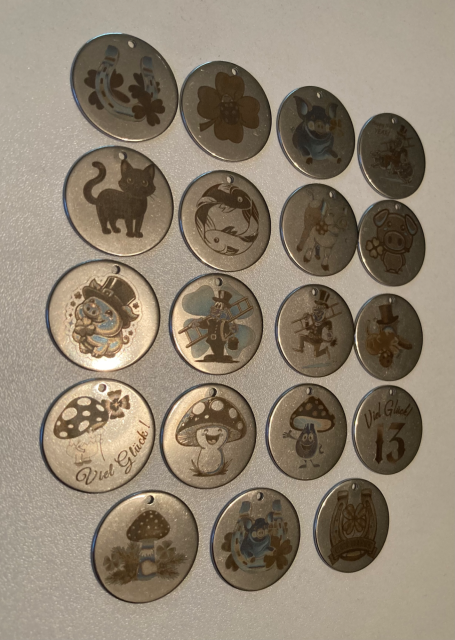 Mehrere runde Tags mit verschiedenen Glückssymbolen in silberner Farbe.