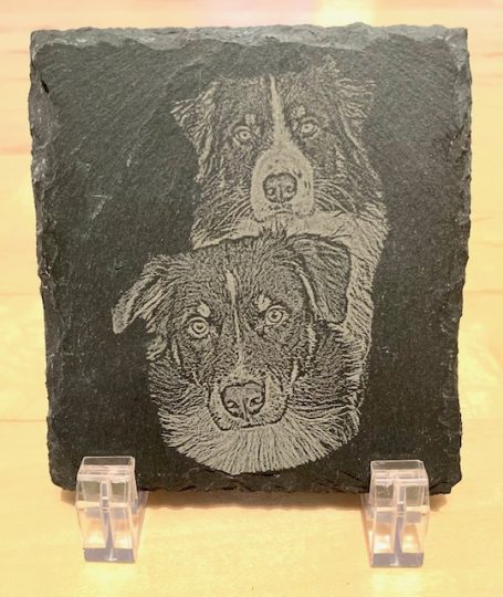 Gravur von zwei Hunden auf einer schwarzen Platte, auf Ständern präsentiert.