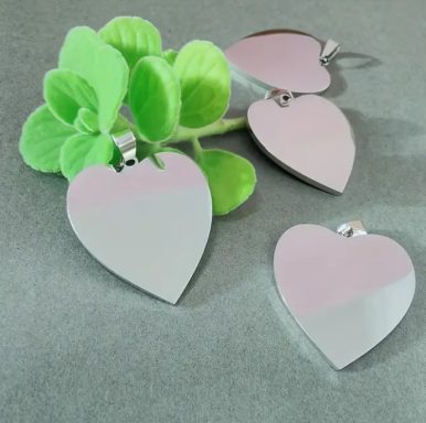 Herzförmige, silberne Anhänger neben einer kleinen grünen Pflanze.