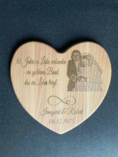 Holzscheibe in Herzform mit Gravur von einem Brautpaar, Datum und Text.