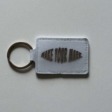 Schlüsselanhänger mit dem Text "MAKE YOUR MARK" auf einem weißen Hintergrund.