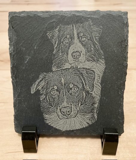 Zwei Hunde in einer gravierten Darstellung auf schwarzem Stein.