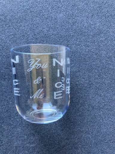 Ein transparentes Glas mit der Aufschrift "You & Me" und dekorativen Buchstaben.