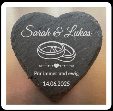 Herzförmiger Stein mit den Namen Sarah und Lukas, dem Datum 14.06.2025 und Eheringen.