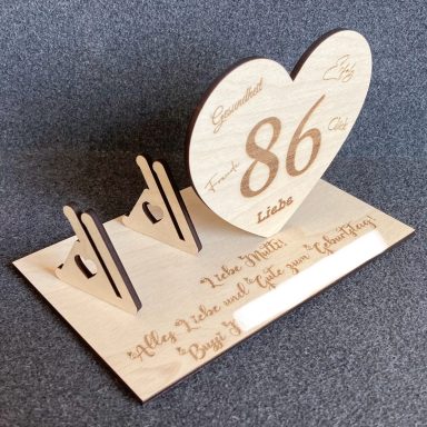 Holzschild in Herzform mit der Zahl 86 und zwei Halterungen, beschriftet.