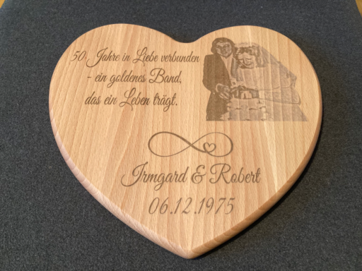 Herzförmiges Holzschild mit gravierter Hochzeitstafel und Datum.