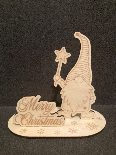 Holzfigur eines Weihnachtswichtels mit einem Stern und der Aufschrift "Merry Christmas".