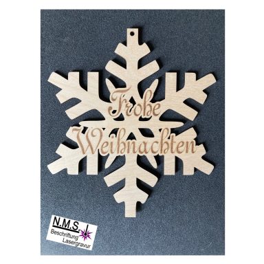 Holzschneeflocke mit der Inschrift "Frohe Weihnachten" auf dunklem Hintergrund.